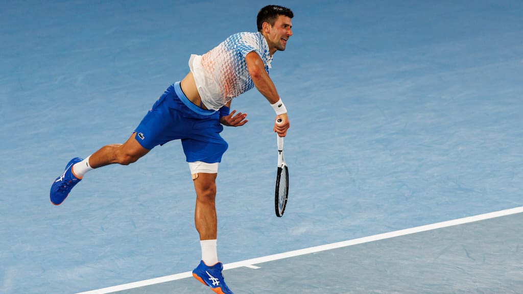 Novak Djokovic following through on a serve during a tennis match.